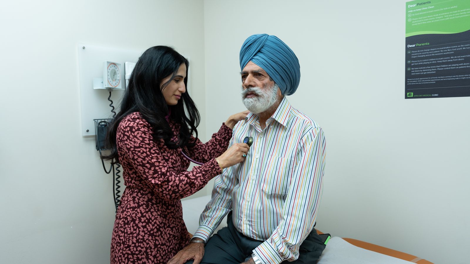 A doctor uses a stethoscope to examine a senior man in an examination room.