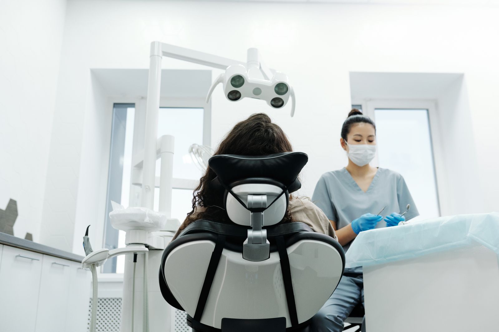 Asian dentist attending to a patient in a modern clinic, focusing on oral health.