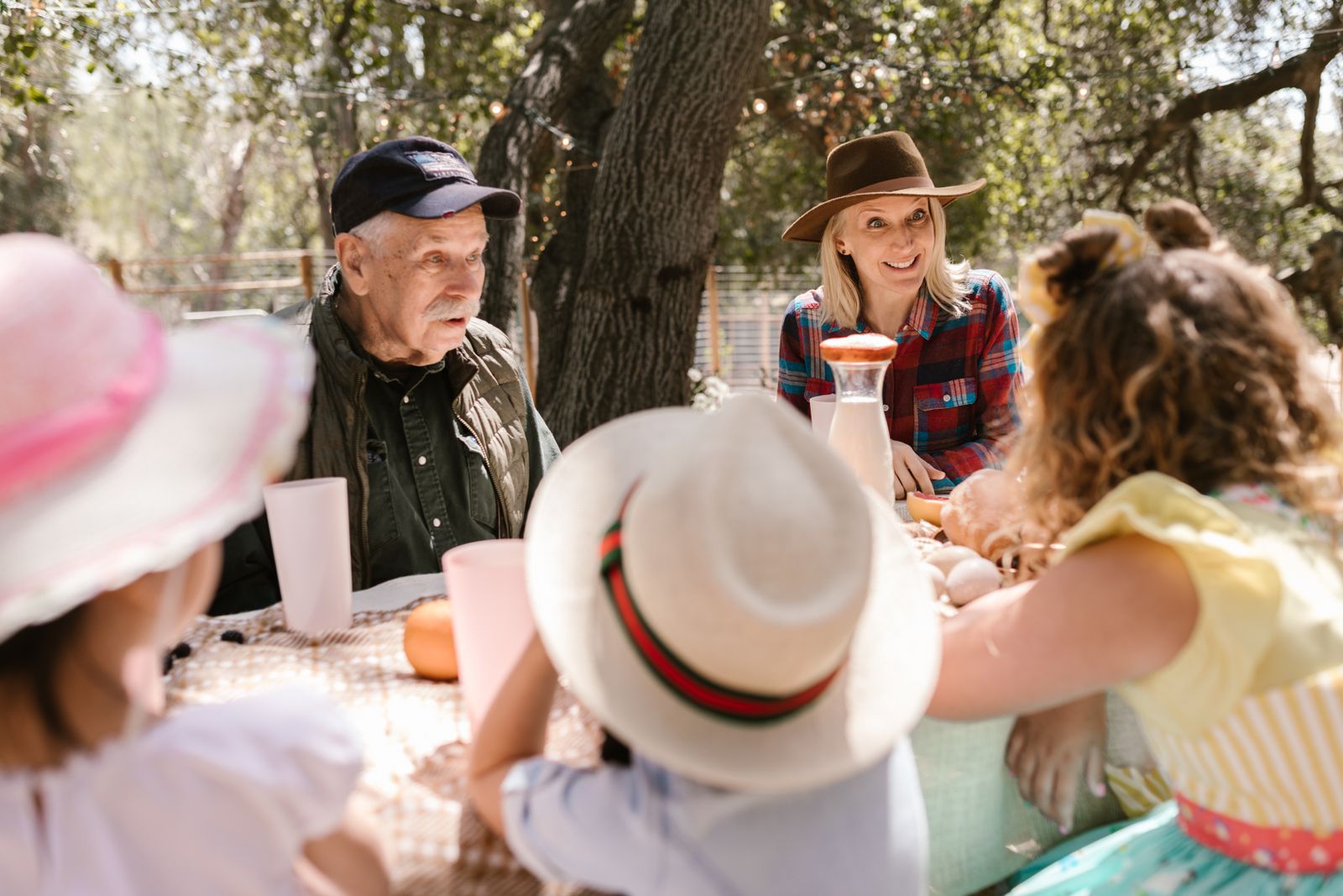 A joyful family picnic with adults and children enjoying a sunny day outdoors.